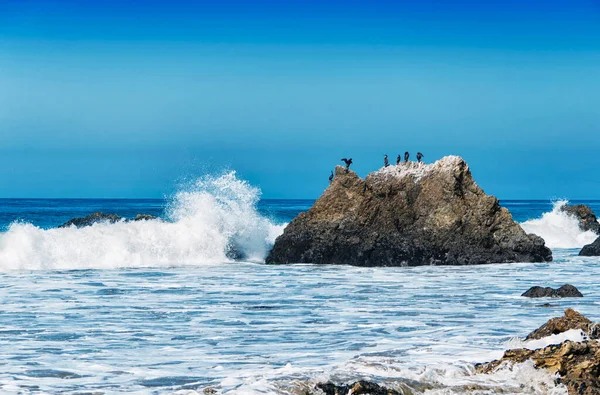 The rocks, waves and pacific ocean at El Matador Beach in California on a sunny cloudless sky day.