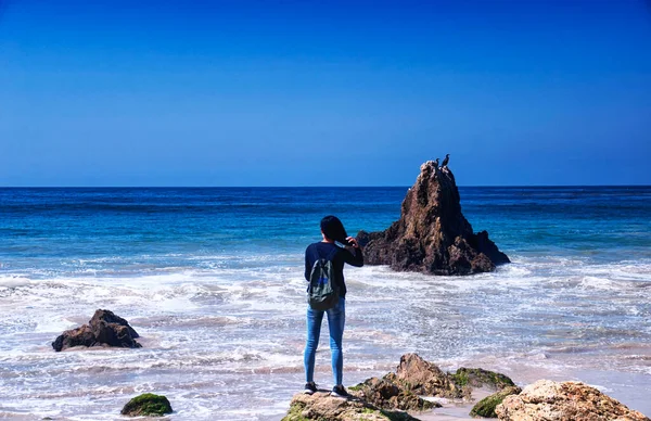 A chinese woman looking at the pacific ocean on El Matador Beach, california.