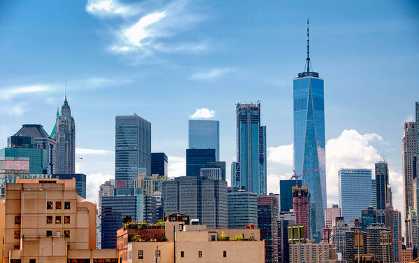 The buildings of the new york city skyline on a sunny day in the summertime.