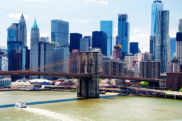 The brooklyn bridge leading into lower manhattan in New York City on a sunny day.