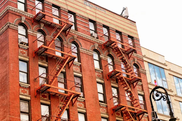 Fire escapes on the exterior of a brick apartment building in New York City.