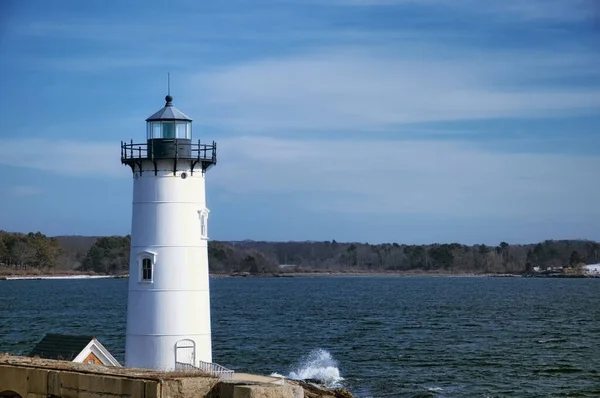 The landmark portsmouth harbor lighthouse covered in snow in New Castle New Hampshire on a sunny blue sky day.
