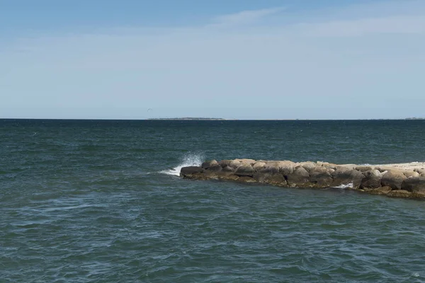 A rock jetty out into Nantucket sound at Edgartown beach on martha\'s vineyard on a sunny day.