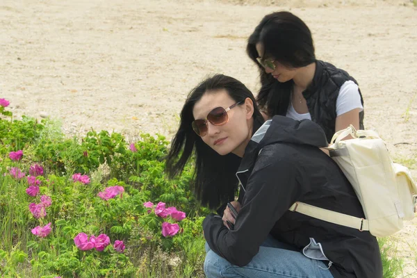 Twee Chinese Vrouw Kijkend Naar Roze Zee Rozen Een Strand — Stockfoto