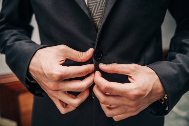 Arka plandaki adam gömleğinin düğmelerini bağlar. 