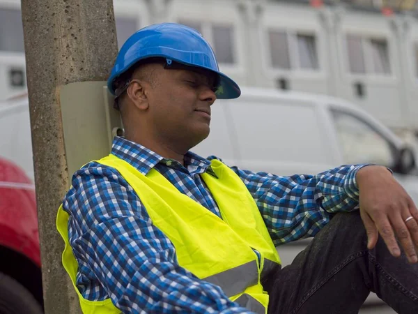 Tired Indian construction worker or civil engineer sitting sleeping and taking a rest