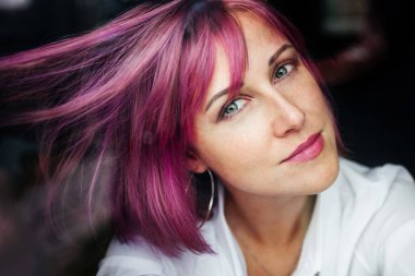 Renkli saçlı kız pencereden bakıyor.