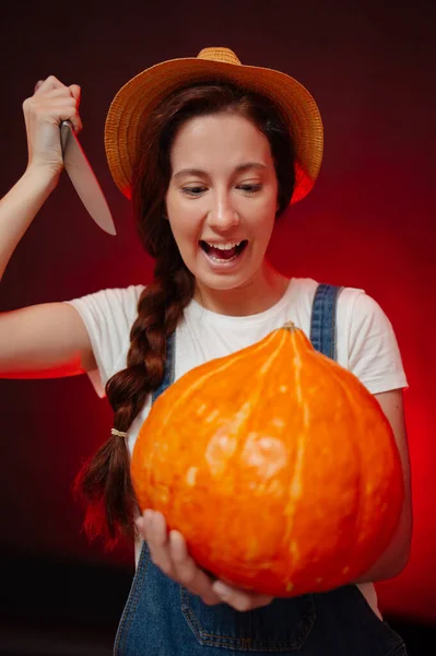 A woman cuts a lantern out of a pumpkin with a knife for the Halloween — Stock Photo, Image