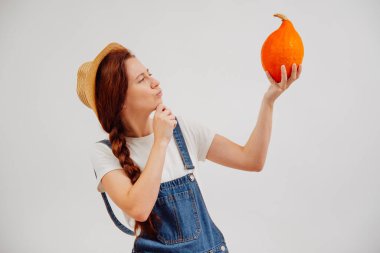 Balkabağı tutan genç bir kadın olgunluğun kalitesini kontrol ediyor..