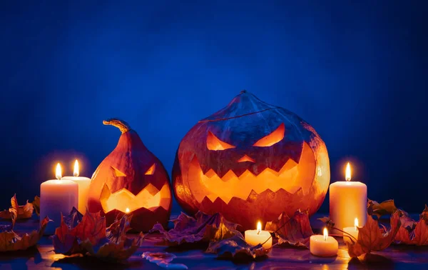 Két őszi töklámpa faragott arccal Halloweenkor gyertyákban.. — Stock Fotó