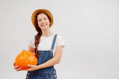 Kadın bahçıvan beyaz arka planda büyük bir balkabağı tutuyor..