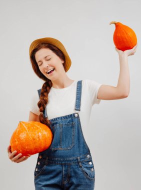 Kadın beyaz arka planda olgun balkabağı hasadını mutlulukla tutuyor..