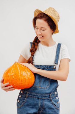 Tulumlu kadın, sonbaharda toplanan büyük bir balkabağı tutuyor..