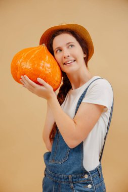 Mutlu çiftçi kadın, olgun bir balkabağını yüzüne bastırıyor..