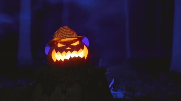 Hátborzongató faragott tök Halloween kék füst az erdőben. — Stock videók