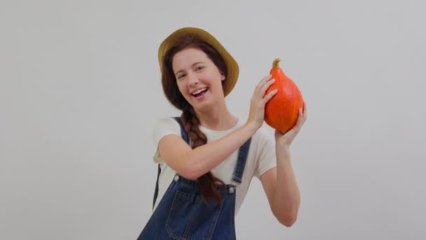 Femme agricultrice sourit en combinaison de denim tenant une citrouille mûre de récolte. — Video