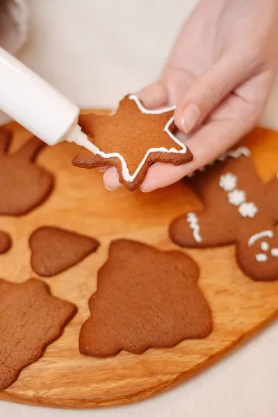 Mujer decora una estrella de jengibre tradicional para las vacaciones de Navidad. — Foto de Stock