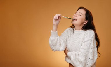 Sarı arka plandaki kazaklı kadının tadı tatlı lolipop gibi..