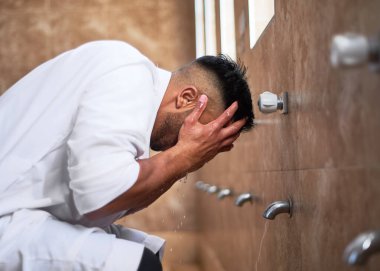 Camide yüzünü temizleyen genç bir Müslüman.