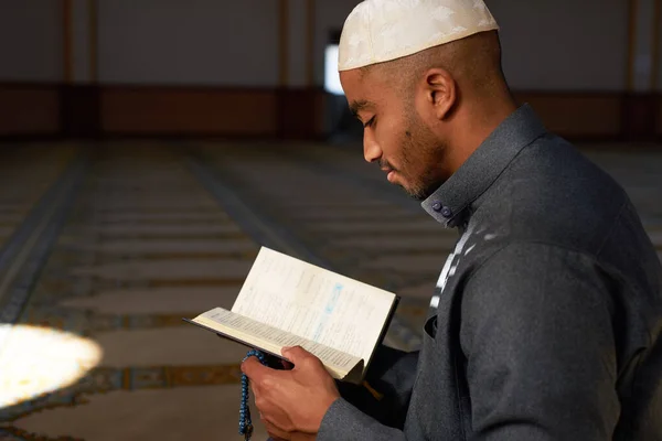 Sidovy av ung Muselman man leende och läsa Quran — Stockfoto