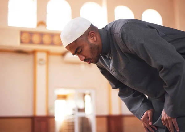 Uma visão lateral de um homem muçulmano curvando-se durante as orações em uma mesquita — Fotografia de Stock