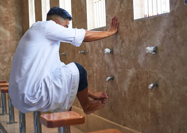 Молодой мусульманин очищает ноги в туалете мечети — стоковое фото