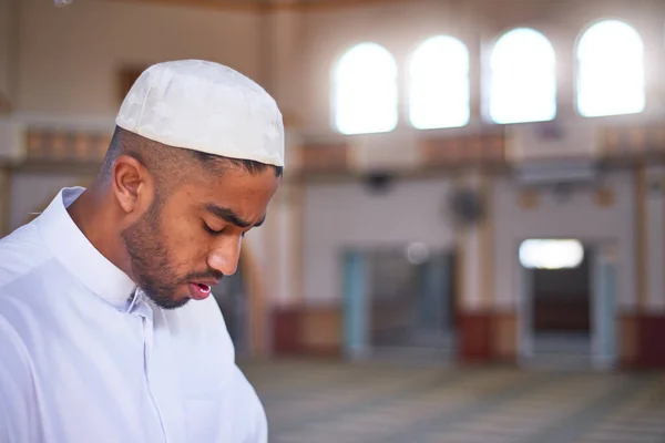 Egy muszlim férfi lehajtja a fejét az imában, miközben egy mecsetben térdel. — Stock Fotó