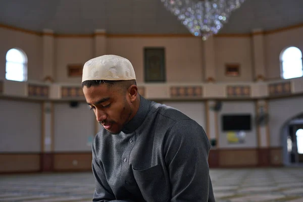 Vista lateral de um homem muçulmano com os olhos fechados em oração dentro de uma mesquita — Fotografia de Stock