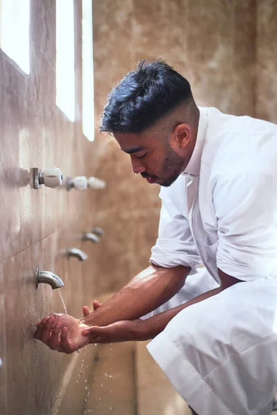 Молодой мусульманин моет руки водой в туалете — стоковое фото