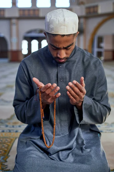 Muszlim férfi imádkozik egy mecsetben térden állva imagyöngyökkel. — Stock Fotó
