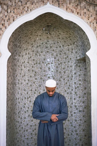 Um jovem muçulmano está de pé com a cabeça curvada em oração — Fotografia de Stock