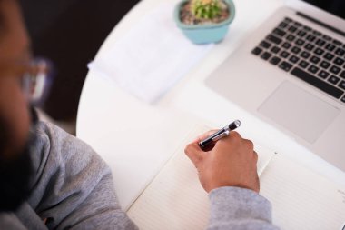 Masasına yazı yazan genç bir adamın omuz üstü fotoğrafı.