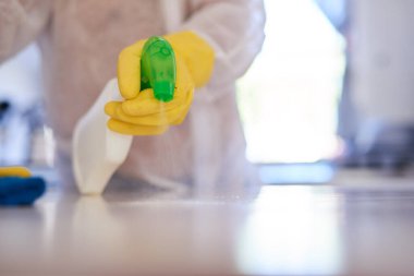 Temizlikçi bir adam mutfak tezgahına dezenfektan sıkar.