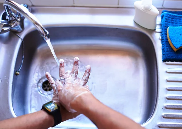 Фотография взрослого мужчины, моющего руки в кухонной раковине — стоковое фото