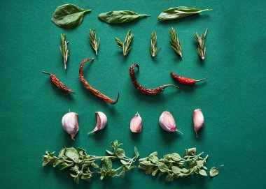 Yeşil arka planda sıralanmış otlar, biber ve sarımsak. Düz yatıyordu
