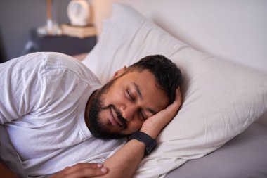 Yetişkin bir adam, sabahları yatağında gülümseyerek huzur içinde uyur.