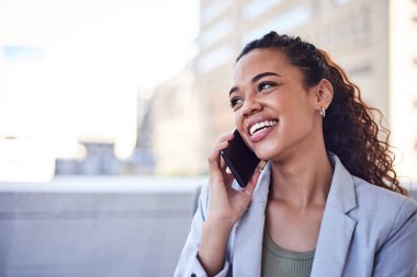 Kıvırcık saçlı genç bir kadın telefonda konuşuyor ve gülüyor.