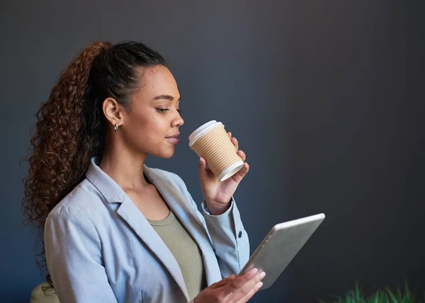 若い女性は彼女のテイクアウトコーヒーとその日のために用意されたデジタルタブレットをすすります — ストック写真