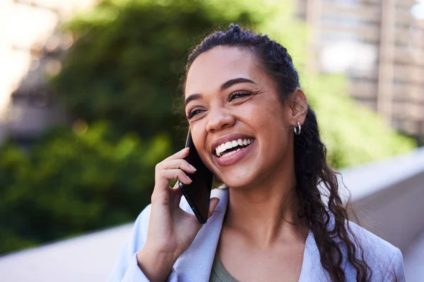 Μια νεαρή γυναίκα χαμογελάει και γελάει ενώ μιλάει στο τηλέφωνο έξω στο μπαλκόνι. — Φωτογραφία Αρχείου