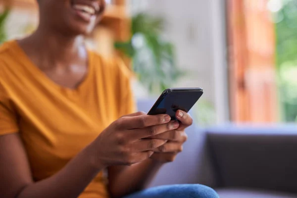 Una foto de cerca de un teléfono móvil en poder de una joven en casa — Foto de Stock