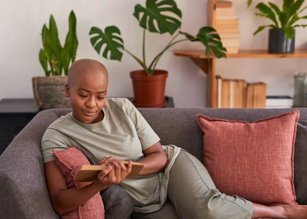 Μια νεαρή γυναίκα διαβάζει ένα μυθιστόρημα στο σπίτι στον καναπέ. — Φωτογραφία Αρχείου
