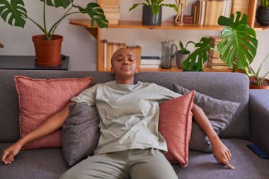 Genç bir kadın yorgun bir şekilde kanepede kestiriyor.