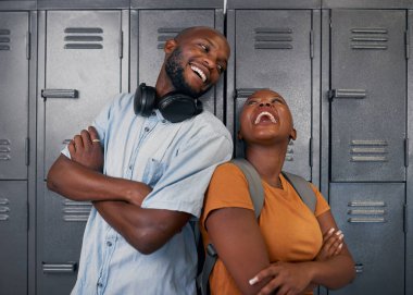 İki genç siyah öğrenci gülüyor ve okuldaki kampüs dolaplarının önünde poz veriyor.