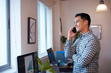 Bir adam telefonda ofisinde duruyor ve sonuçların grafiklerine bakıyor.
