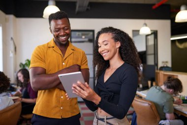 Genç, çok ırklı bir kadın meslektaşına dijital tablet hakkında bilgi veriyor.