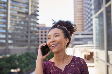 A young multi-ethnic woman takes a call on the balcony of a city office building. High quality photo