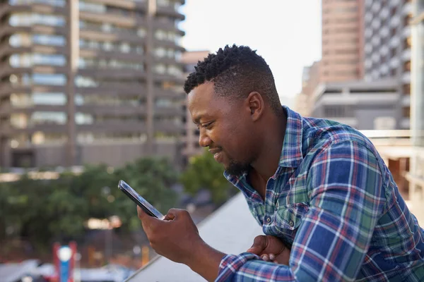 Ofis balkonunda kahve molası sırasında siyah bir işadamı cep telefonundan mesaj atıyor. Yüksek kalite fotoğraf