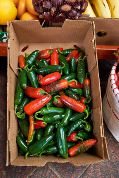 A cardboard box filled with red and green chili at a vegetable market. High quality photo
