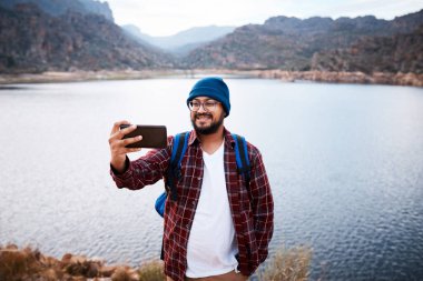 Mutlu bir yürüyüşçü zirvede arka planda bir gölle selfie çeker. Yüksek kalite fotoğraf