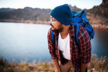 Bir yürüyüşçü göl manzaralı bir dağa tırmanırken mola alır. Yüksek kalite fotoğraf